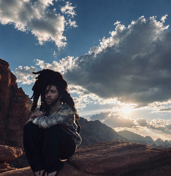 6xrpse (André Charles) on red rocks under a cloudy sky, September 2026